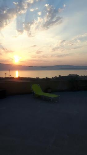 a green bench sitting on the beach at sunset at Affittacamere da chris in Reggio Calabria