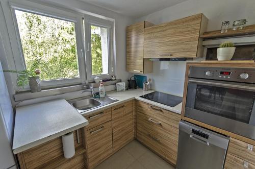 a kitchen with wooden cabinets and a sink and a window at Apartament dwupokojowy Poznań- blisko centrum in Poznań