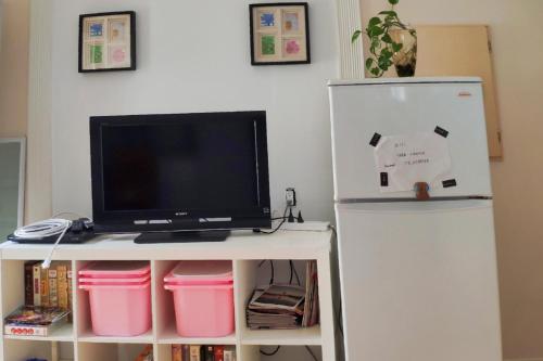 a tv on a white table next to a refrigerator at Helen's House / Close to Skytrain and Airport in Vancouver