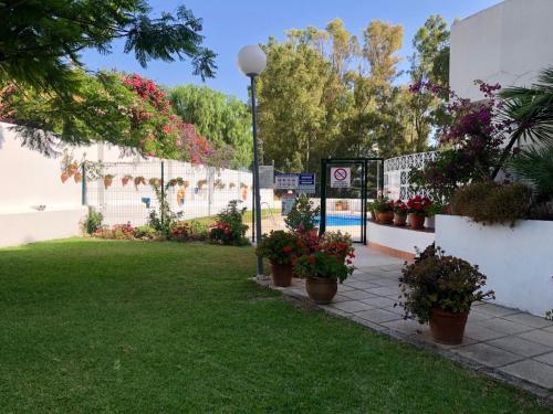 een tuin met potplanten en een bord in het gras bij Studio Orquídea Beach 4 in Fuengirola