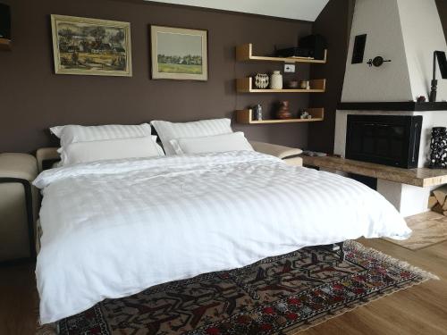 a bedroom with a large white bed and a fireplace at Holiday House Red Deer in Preddvor