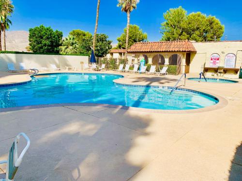 a large swimming pool in a resort with palm trees at Desert Getaway in Desert Hot Springs