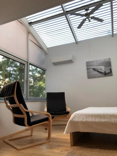 a bedroom with a bed and a chair and a ceiling fan at NIDALIVING Romantic Apartment Under the Stars in Nida