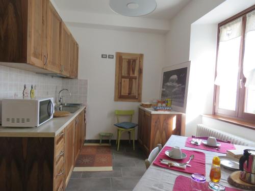 eine Küche mit einer Mikrowelle und einem Tisch darin in der Unterkunft B&B Casa Taralin in Teglio