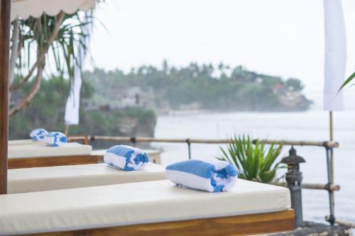 four beds with blue and white pillows on them at Twilight Ceningan in Nusa Lembongan