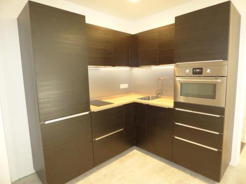 La cuisine est équipée d'armoires en bois sombre et d'un four en acier inoxydable. dans l'établissement LOFT-HOLIDAY 5 Appartement spacieux à proximité de la plage, à Pinet