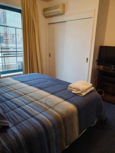 a bedroom with a bed with a blue blanket and a window at Apartamento DELUXE Edificio Millenium in Mendoza