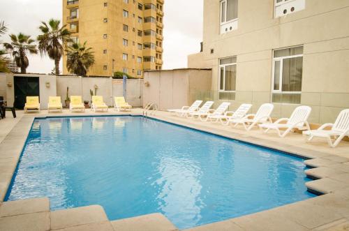 a swimming pool with lounge chairs and a hotel at Hotel Diego De Almagro Arica in Arica