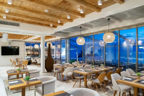 um restaurante com mesas e cadeiras e janelas grandes em Sea Level Hotel - Adults Only 16 plus em Polykhrono