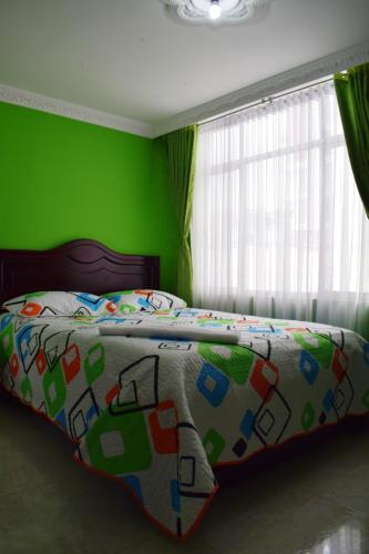 a bedroom with a bed with a green wall at Hotel Londres in Pasto