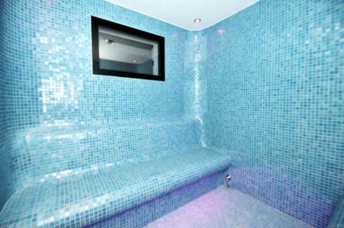 a blue tiled bathroom with a television on the wall at Apartament TOP Pięć Mórz basen&SPA in Sianozety