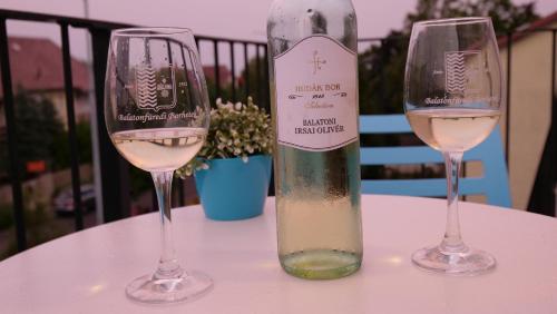 two wine glasses sitting on a table with a bottle of wine at Anna Villa Füred Boutique Rooms in Balatonfüred