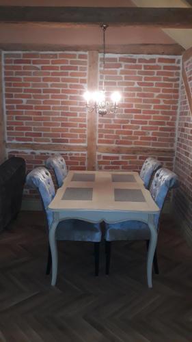 a table with blue chairs in a room with a brick wall at Vanalinna apartement in Viljandi