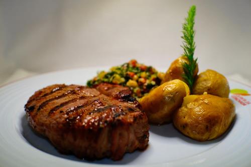 a plate of food with meat potatoes and vegetables at Hotel Rural Quinta da Conchada in Aguieira