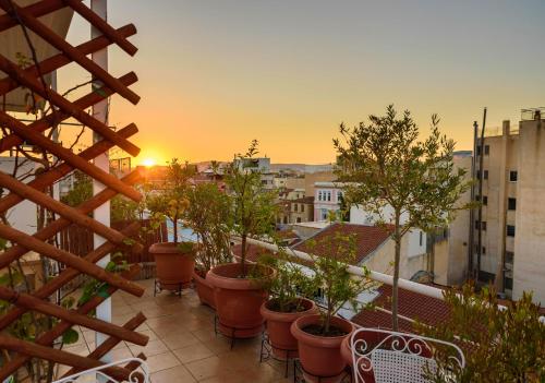 a balcony with potted plants and a sunset on a city at Acropolis Eye Loft in Athens