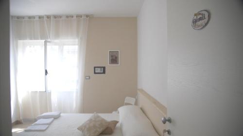 a white bedroom with a bed and a clock on the wall at Binario 2 in San Giorgio a Cremano