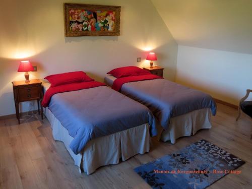 a bedroom with two beds with red pillows and two lamps at Rose cottage in Pontrieux
