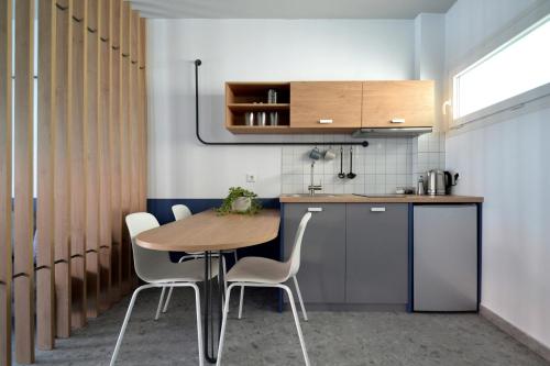 cocina con mesa de madera y sillas blancas en Voula Seaside Apartments en Kallithea Halkidikis
