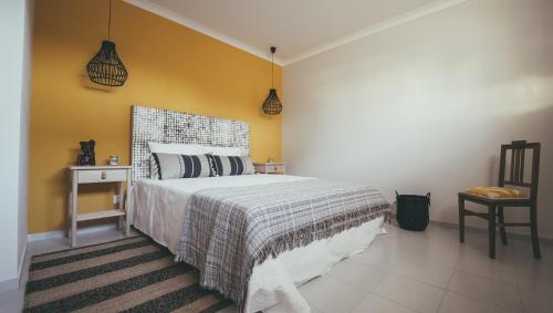 a bedroom with a bed and a yellow wall at Vila Milreu Guest House in Estói