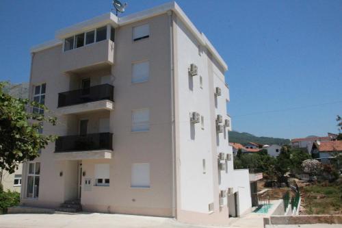ein hohes weißes Gebäude mit Seitenfenstern in der Unterkunft Zigovic Apartmani in Bar