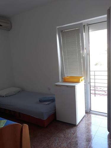 a small bedroom with a bed and a window at Apartmani Stojanović in Sutomore