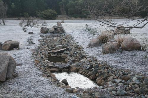 a river with rocks and a man sitting on top at Granite Belt Retreat and Brewery in Stanthorpe