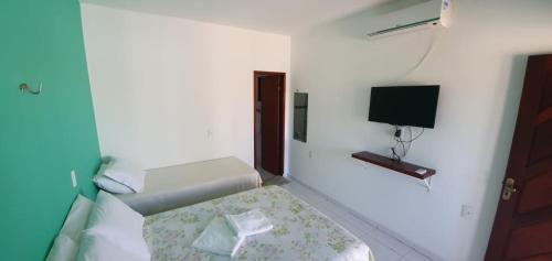 a small white room with a bed and a television at Pousada Villa Galinhos in Galinhos