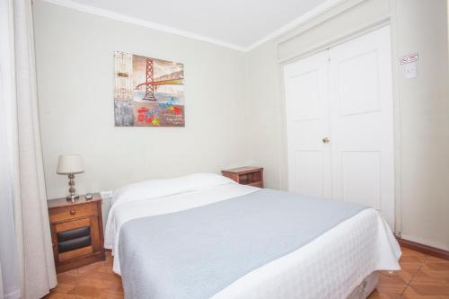 a white bedroom with a white bed and a window at Hotel Santisimo in Viña del Mar