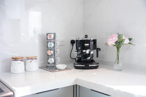 a kitchen counter with a coffee maker and a vase of flowers at Amazing London in London