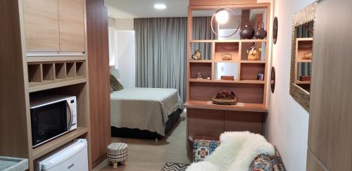 ペドラ・アズールにあるFlat em Pedra Azulのベッドとテレビ付きの小さな客室です。