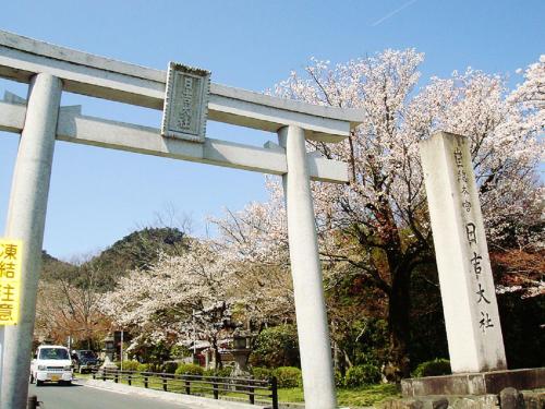 a torii gate in front of a road with trees at Ogoto Onsen Yunoyado Komolebi in Otsu