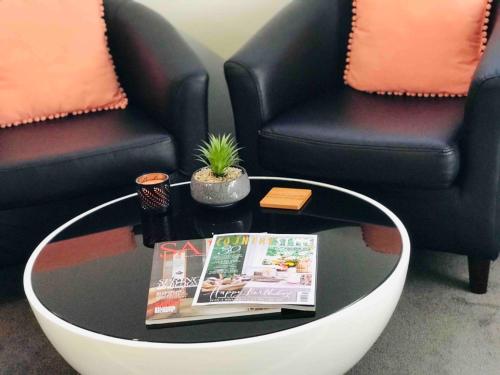 a coffee table with a magazine and two chairs at Adelaide Hills Escape in Woodside