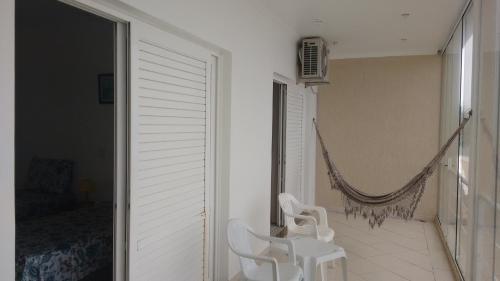 a room with two white chairs and a hammock at CASA - FRENTE PARA O MAR in Itanhaém
