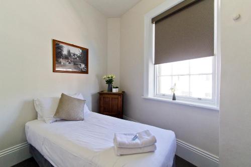 a bedroom with a white bed and a window at Deloraine Hotel in Deloraine