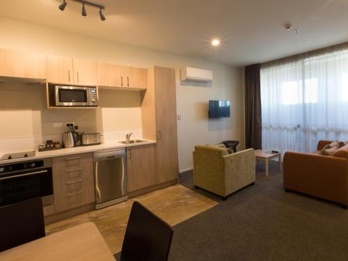 基督城的住宿－Ramada Suites by Wyndham Christchurch City，厨房以及带沙发和桌子的客厅。