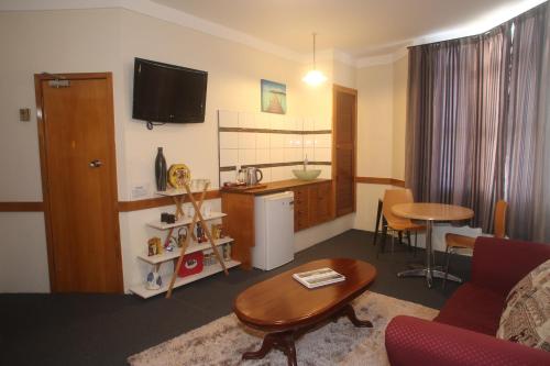 a living room with a table and a kitchen at The Grand Hotel Wanganui in Whanganui