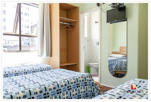 Una habitación de hotel con dos camas y un espejo. en Bandeira Hotel, en Caxias do Sul