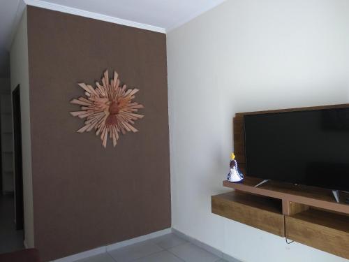 uma sala de estar com televisão e um relógio na parede em Casa aconchegante próxima a Basílica! em Aparecida