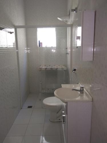 een witte badkamer met een toilet en een wastafel bij Casa aconchegante próxima a Basílica! in Aparecida
