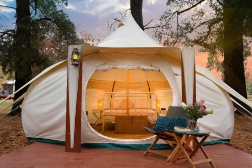 a tent with a bed and a table and a chair at Daylesford Holiday Park in Daylesford