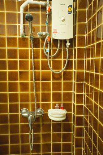 a yellow tiled bathroom with a shower with a nozzle at The Odyssey Chiang Mai in Chiang Mai