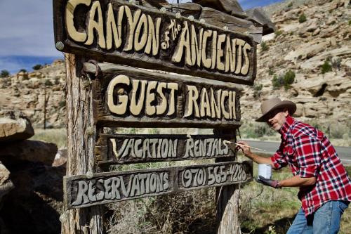 Canyon Of The Ancients Guest Ranch في كورتيز: رجل واقف بجانب لافته في الصحراء