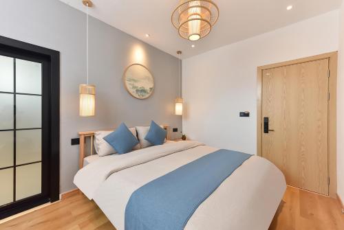 a bedroom with a large bed with blue pillows at Yifangyan - Tingyuan Qingshe Hostel in Fenghuang