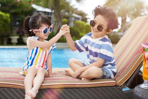 a boy and a girl sitting on a chair by a pool at The Langham, Shenzhen in Shenzhen