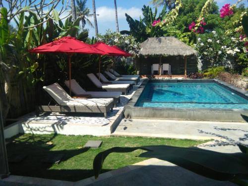 a swimming pool with chairs and umbrellas next to at Villa Kinagu in Gili Meno