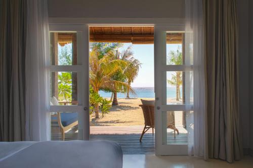 a bedroom with a view of the beach through a door at Meno House - Adults Only in Gili Meno
