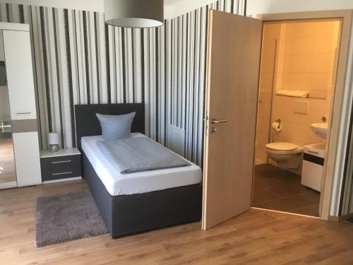 ein kleines Schlafzimmer mit einem Bett und einem WC in der Unterkunft Pension Sonntag Ferienwohnungen in Ingolstadt