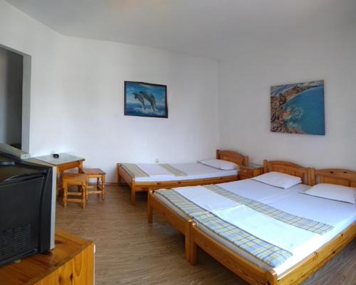 a room with four beds and a tv and a table at Guest House Dzhegosh in Primorsko