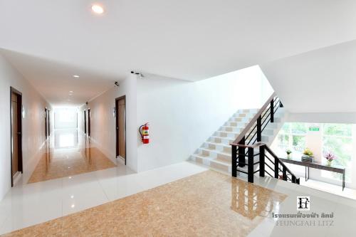 a hallway of a house with white walls and stairs at Feungfah Litz in Phetchabun