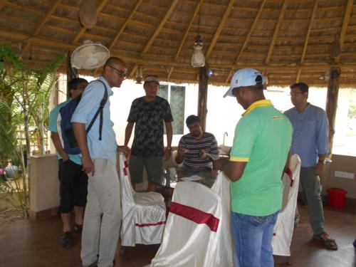 a group of men standing around a table in a room at Solitary Nook in Gosāba